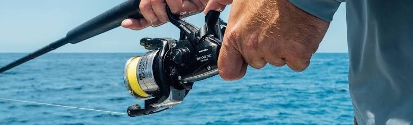 Dogfish Tackle & Marine Shimano Baitrunner OC 8000 saltwater spinning reel with yellow line, black graphite body, and aluminum handle.
