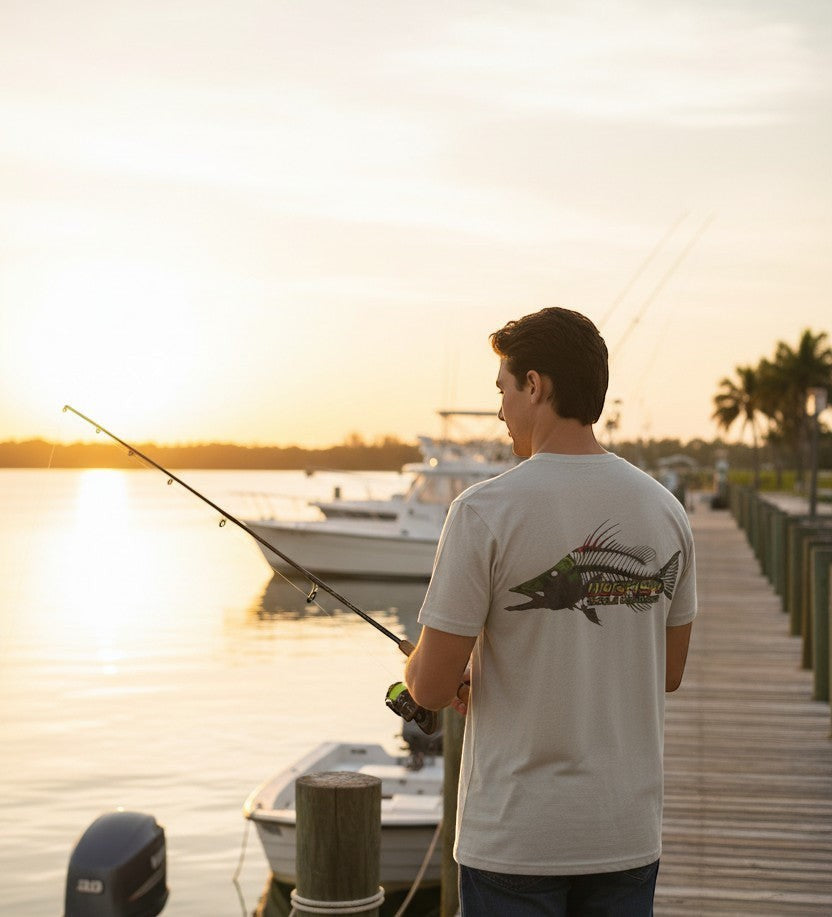 Man fishing on a dock at sunset with a boat and scenic water background.