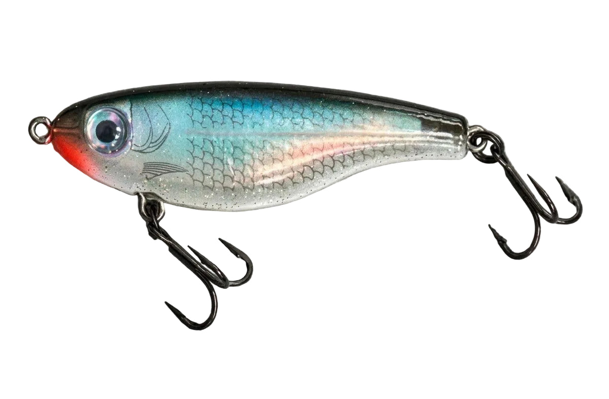 A hard bait fishing lure with a realistic fish design, featuring a silver body with blue and green iridescence, a red belly, and black treble hooks, shown on a textured gray background.
