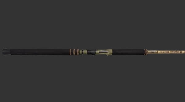 A premium fishing rod with a black handle and gold-colored metallic sections, shown diagonally against a dark, moody studio background.