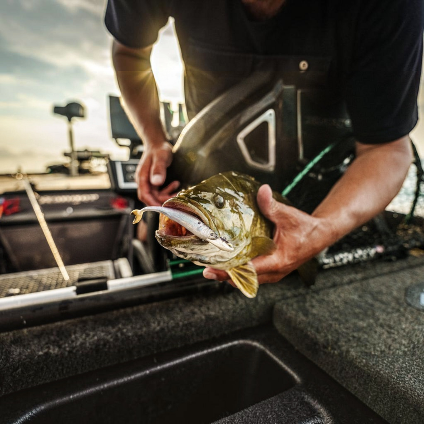 Dogfish Tackle & Marine 6th Sense Strobe Minnow lure in a largemouth bass mouth, held by an angler on a fishing boat.