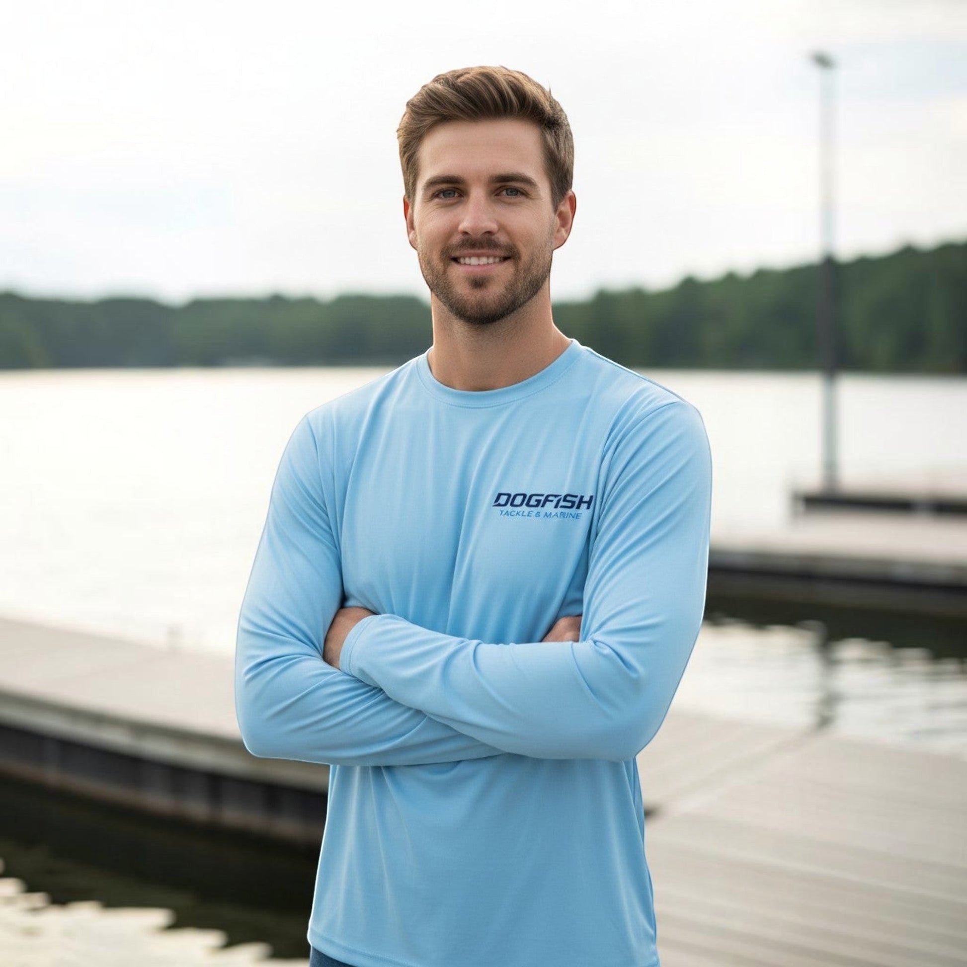 Dogfish Tackle & Marine light blue microfiber long sleeve shirt with logo. Model wears shirt with arms crossed.