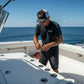 Dogfish Tackle & Marine trucker hat with Florida flag patch, mesh back, and structured front panels worn by a man on a boat.
