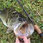 Dogfish Stik Signature Series graphite fishing rod with cork handle next to a large bass on grass.