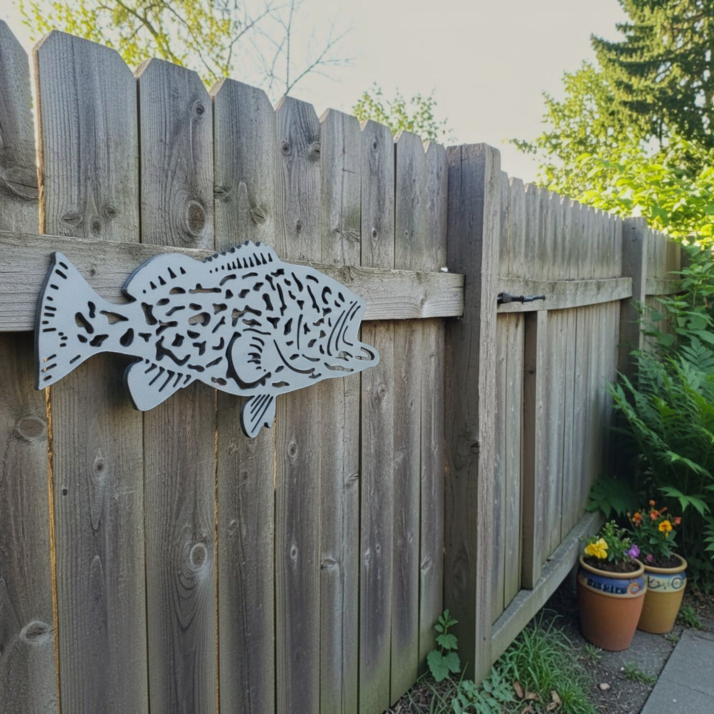 Dogfish Tackle & Marine metal fish wall art mounted on a wooden fence for coastal outdoor garden decor