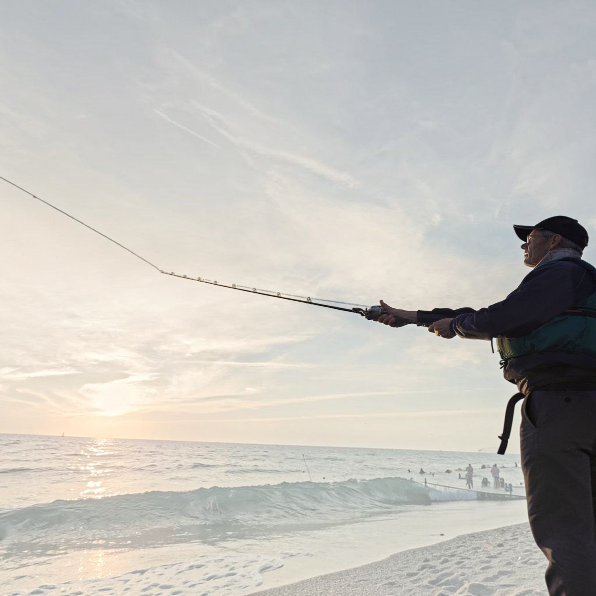 Dogfish Tackle & Marine angler casting a fishing rod with Seaguar INVIZX fluorocarbon line at sunset on the beach