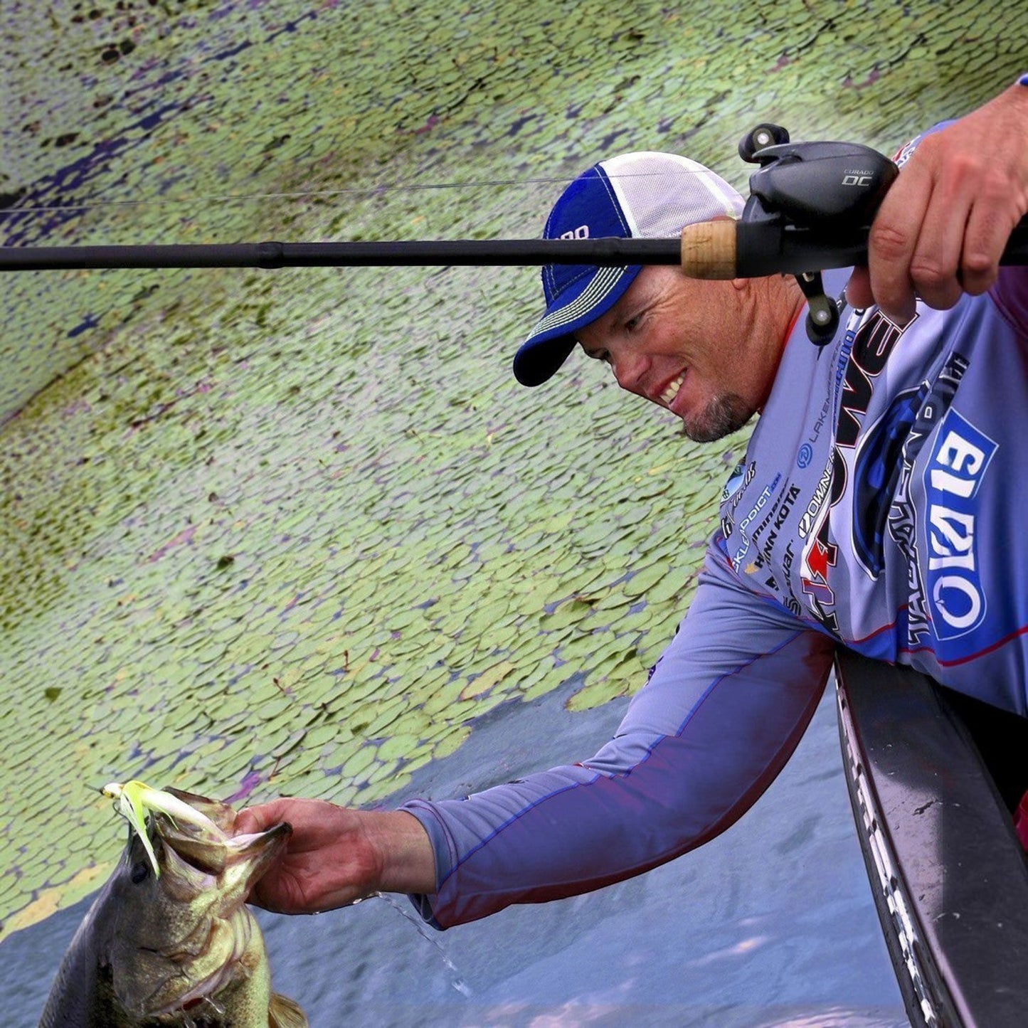 Dogfish Tackle & Marine angler with a bass, holding a Shimano Curado DC baitcasting reel and rod.