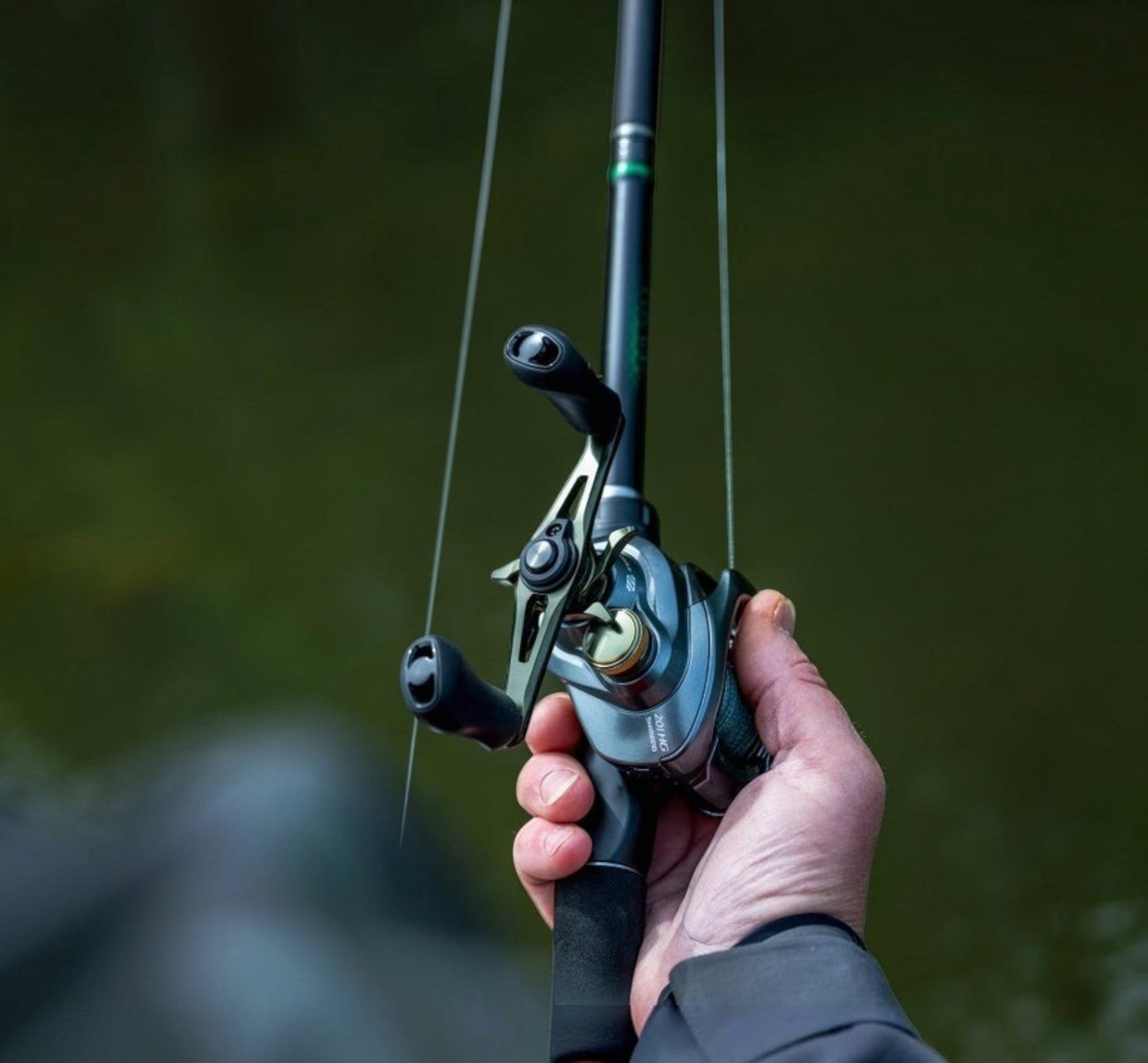 Dogfish Tackle & Marine Shimano Curado DC baitcasting reel in gunmetal grey with gold accents, held by a hand.
