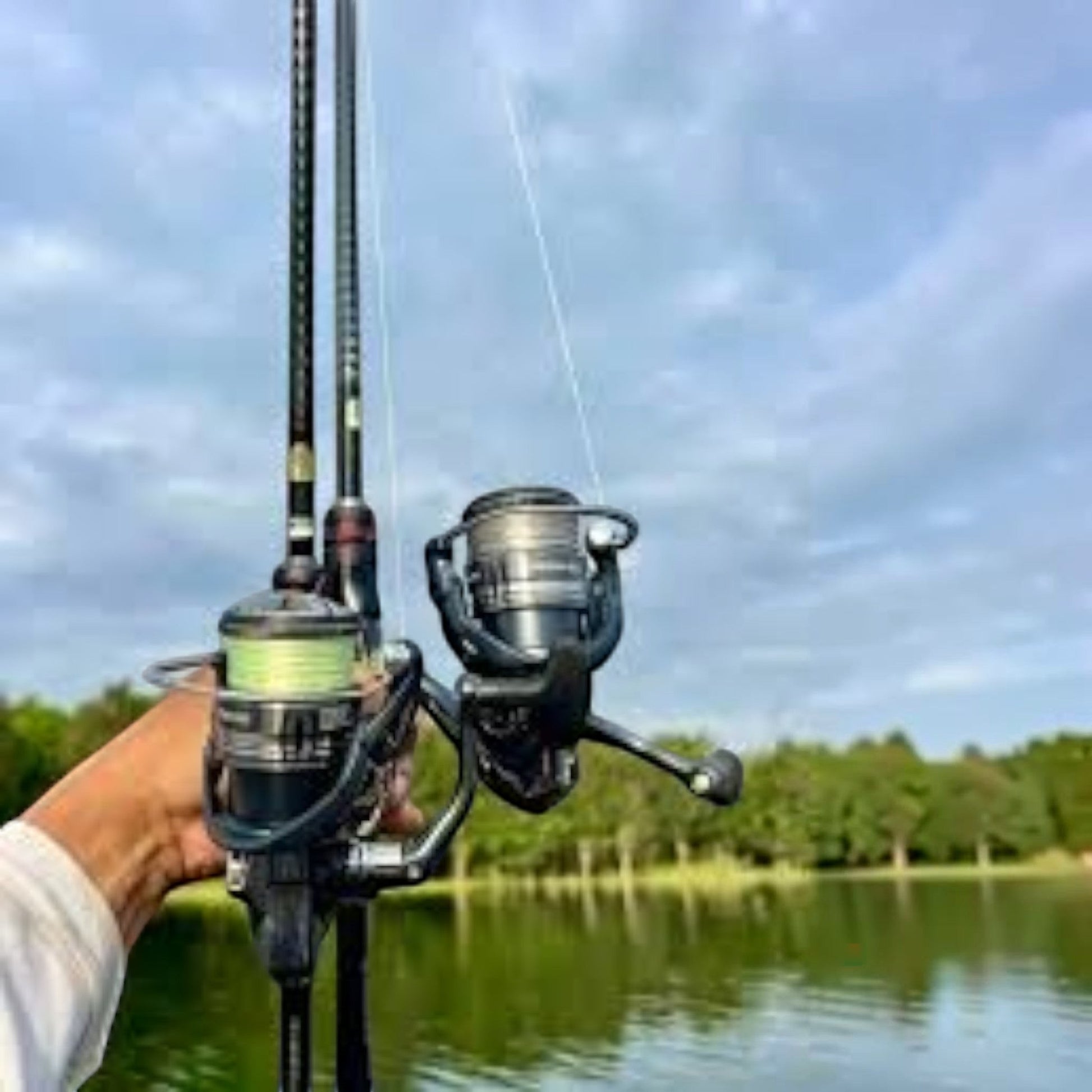 Dogfish Tackle & Marine Shimano Miravel spinning reel with light green line on a fishing rod, held by a person near a lake.