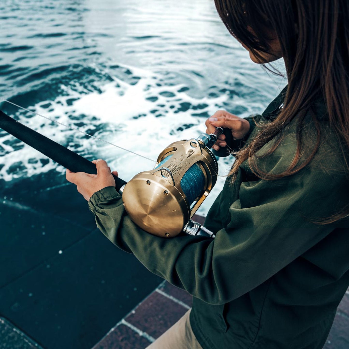 Dogfish Tackle & Marine Shimano Tiagra 2-speed lever drag trolling reel with blue fishing line, held by a person fishing.