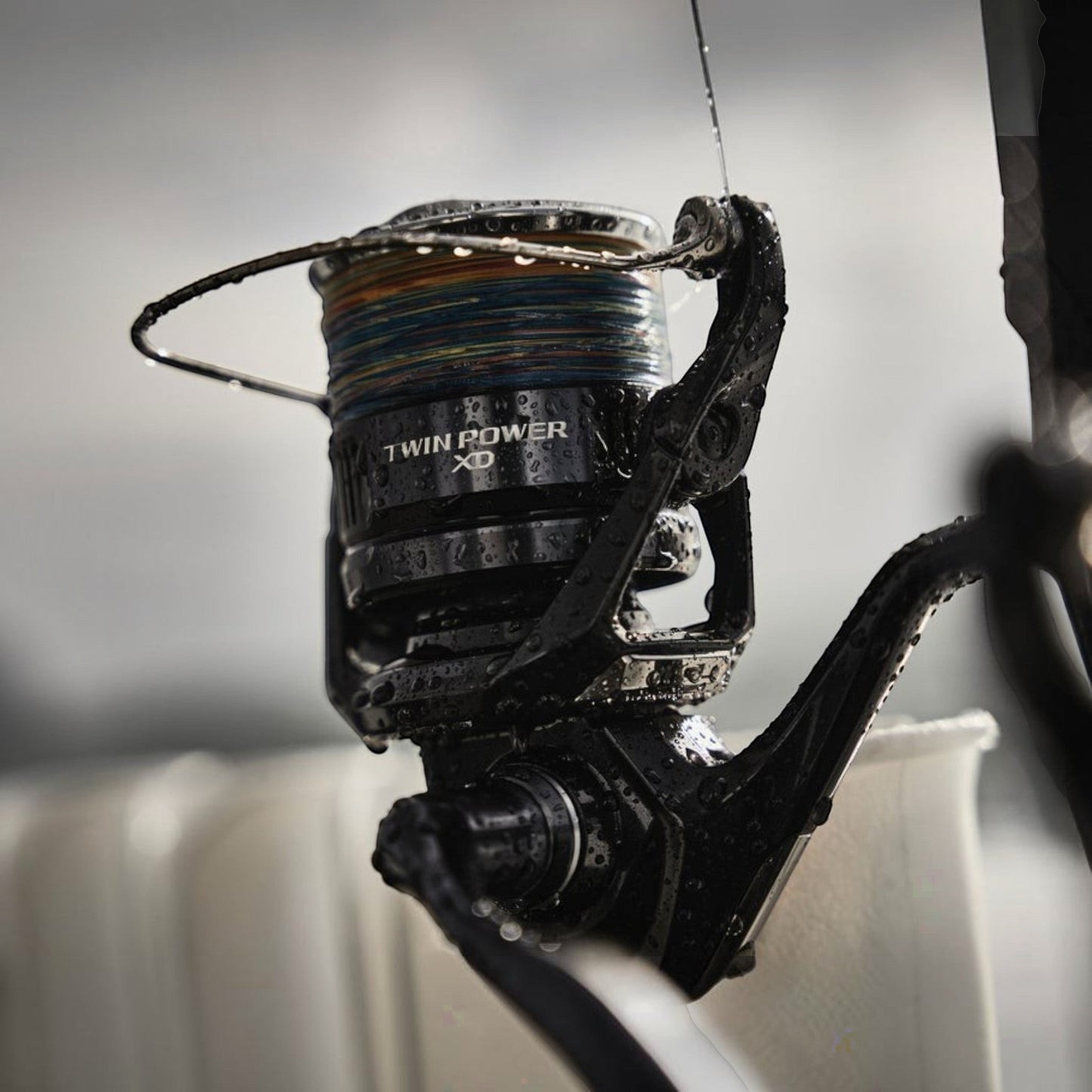 Dogfish Tackle & Marine Shimano Twin Power XD FB spinning reel, black, with multi-colored fishing line and water droplets.