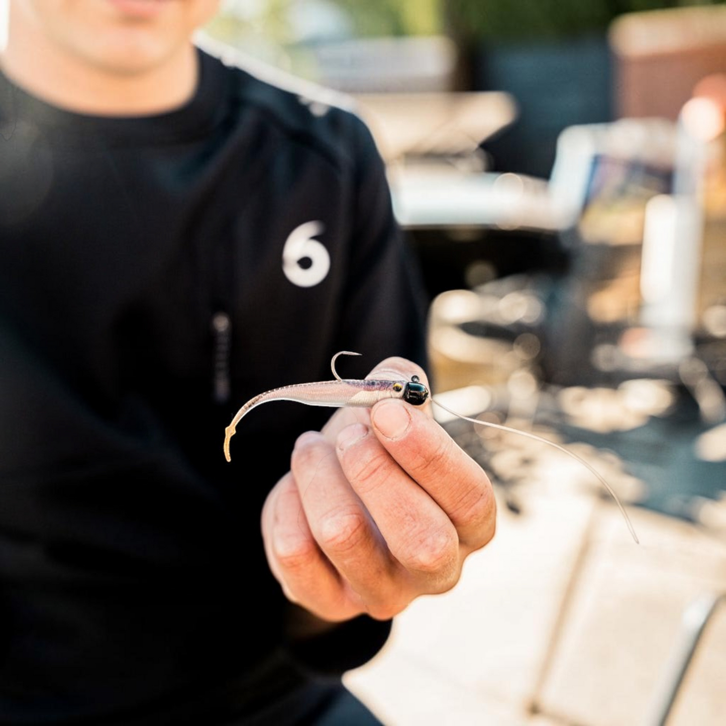 Dogfish Tackle & Marine 6th Sense Strobe Minnow soft plastic bait held by an angler for realistic fishing presentation