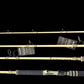 Four fishing rods displayed horizontally against a solid black background, showing both the blank and the wrapped handle sections with tags attached.